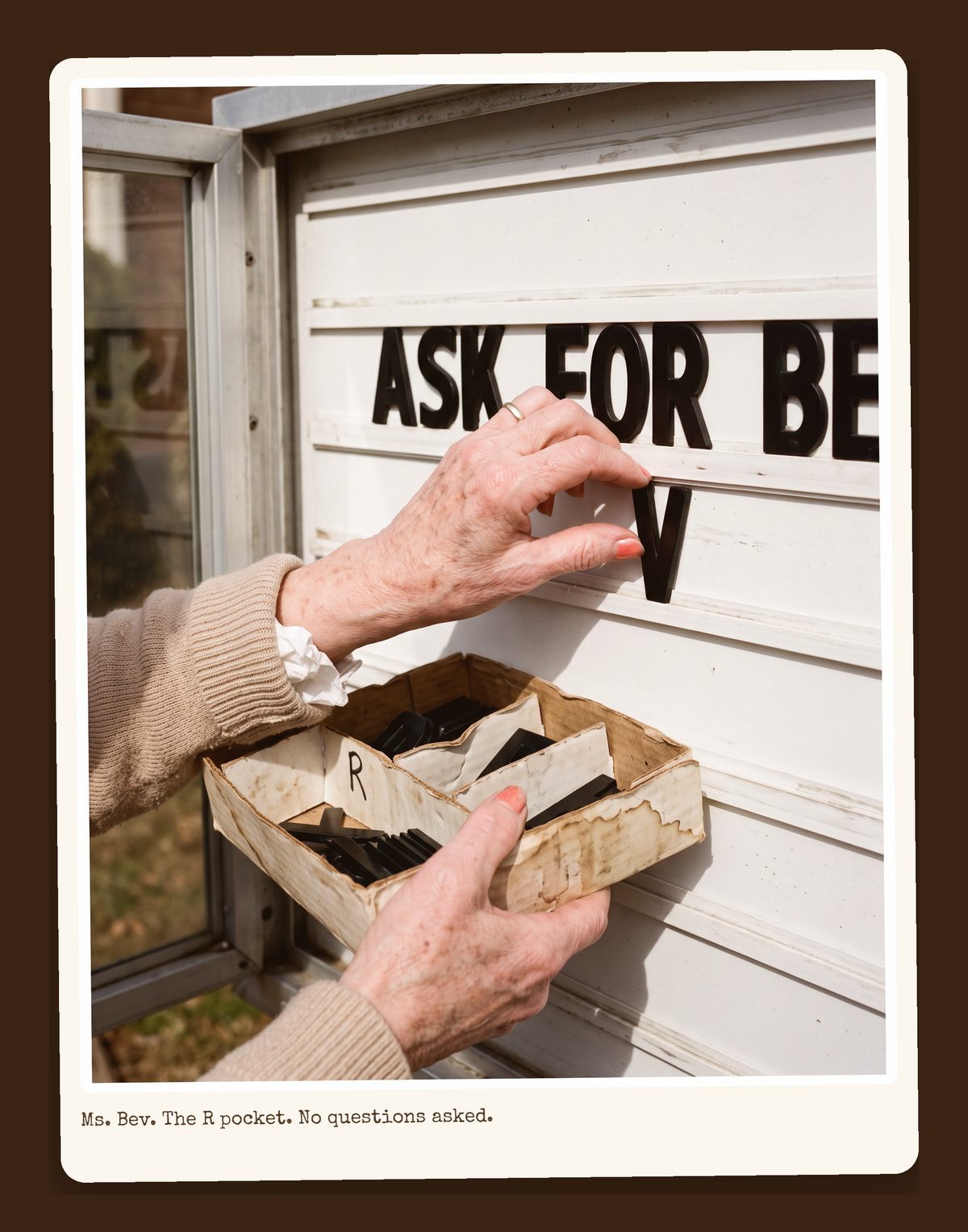 Bev's hands at the changeable-letter sign, the R pocket empty