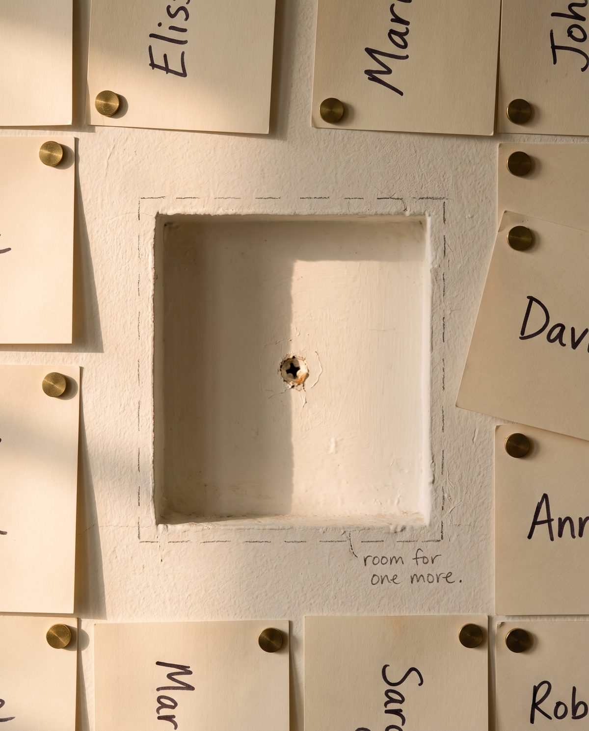 A wall of name cards with one bay left open, labelled room for one more